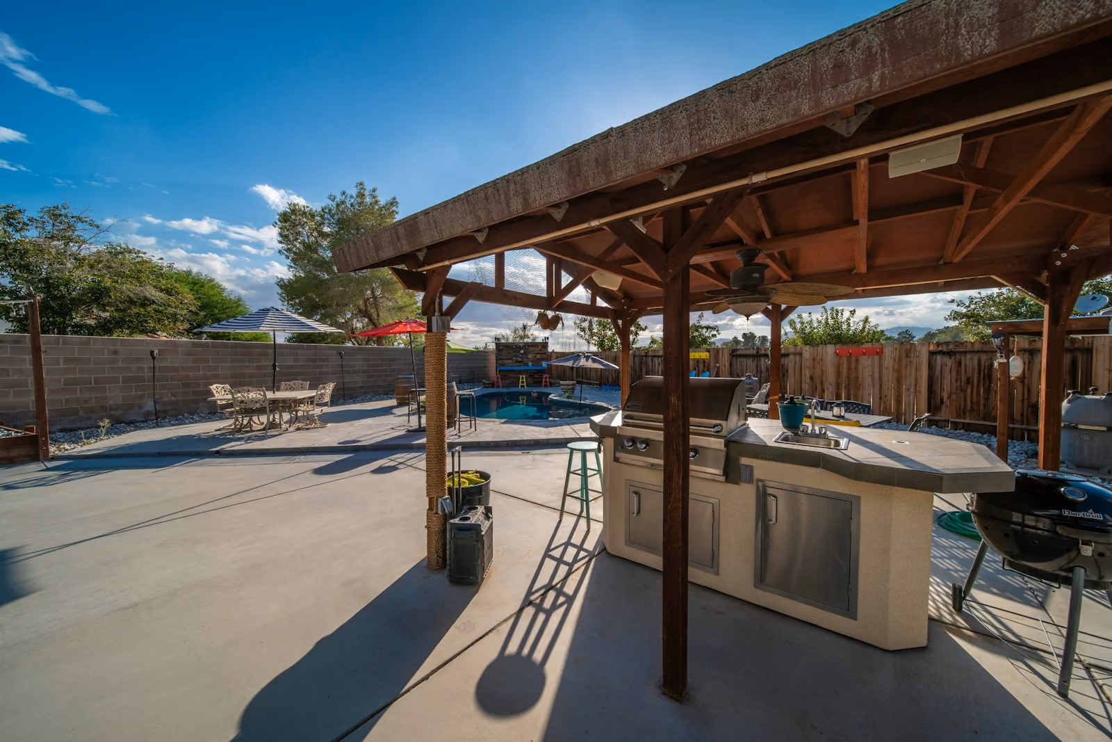 Covered backyard patio with a grill and table