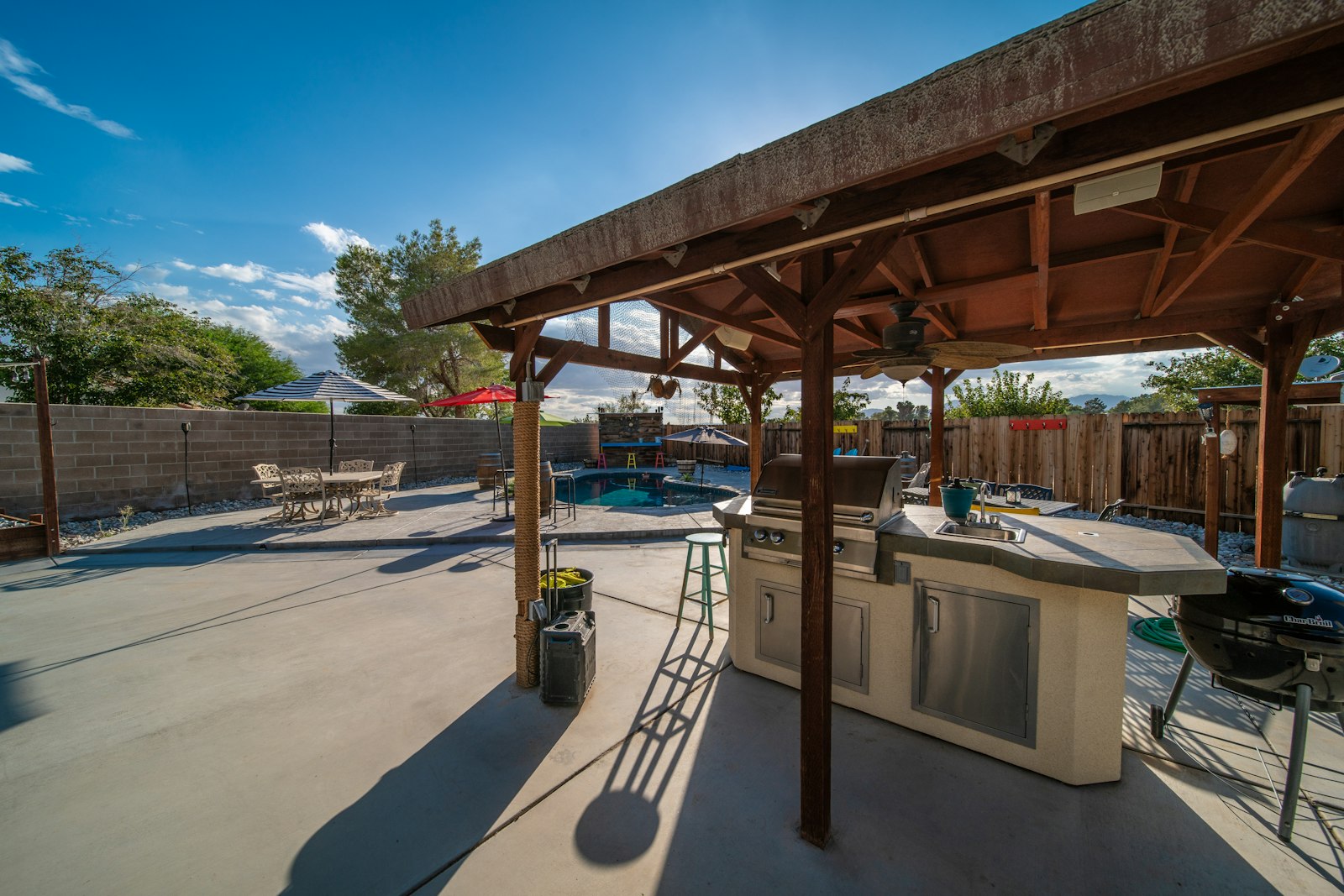 Covered backyard patio with a grill and table