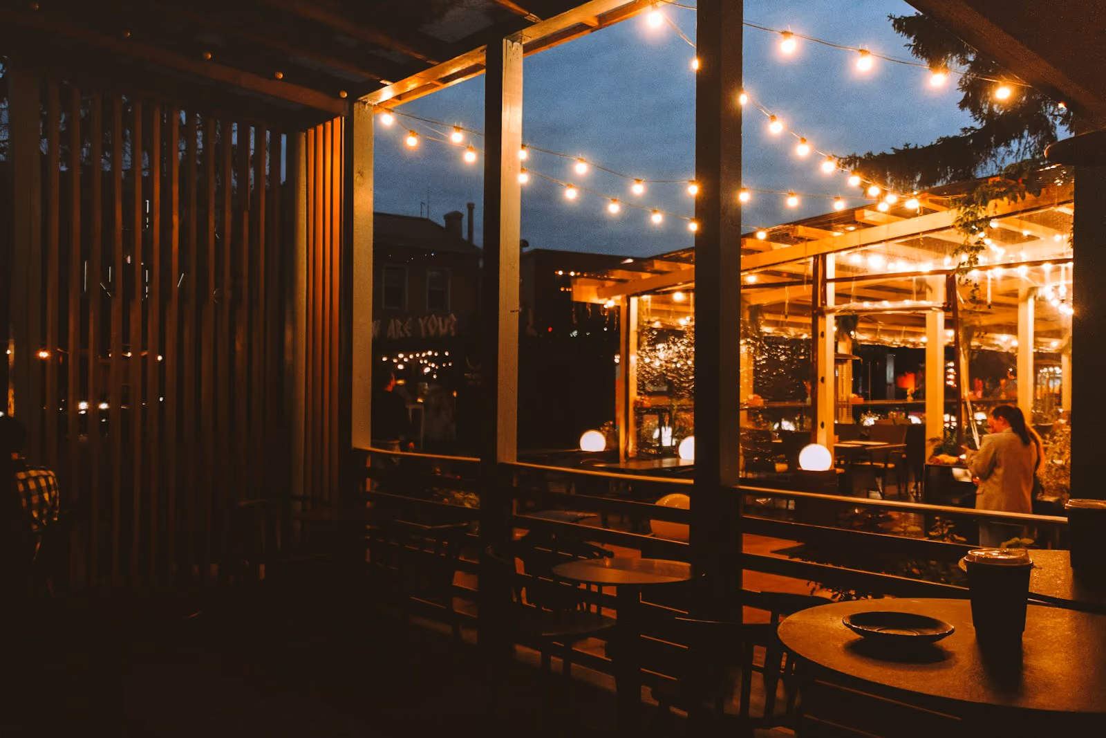 Outdoor cafe seating with string lights in the evening