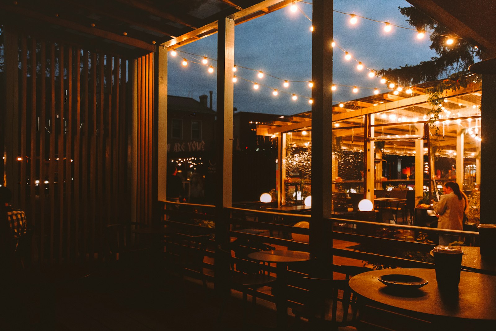 Outdoor cafe seating with string lights in the evening