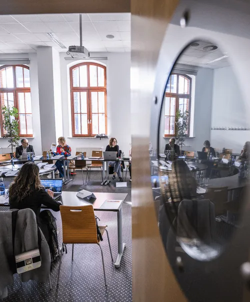 ECIU collaborative workspace with participants working on laptops in historic building with arched window