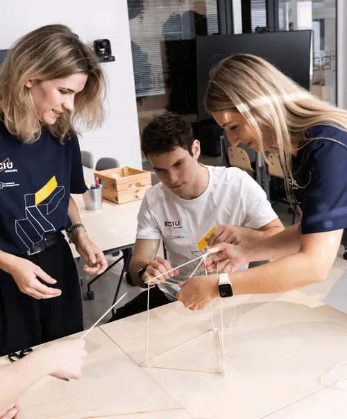 ECIU University students collaborating on hands-on engineering challenge building structural model with rods and strings