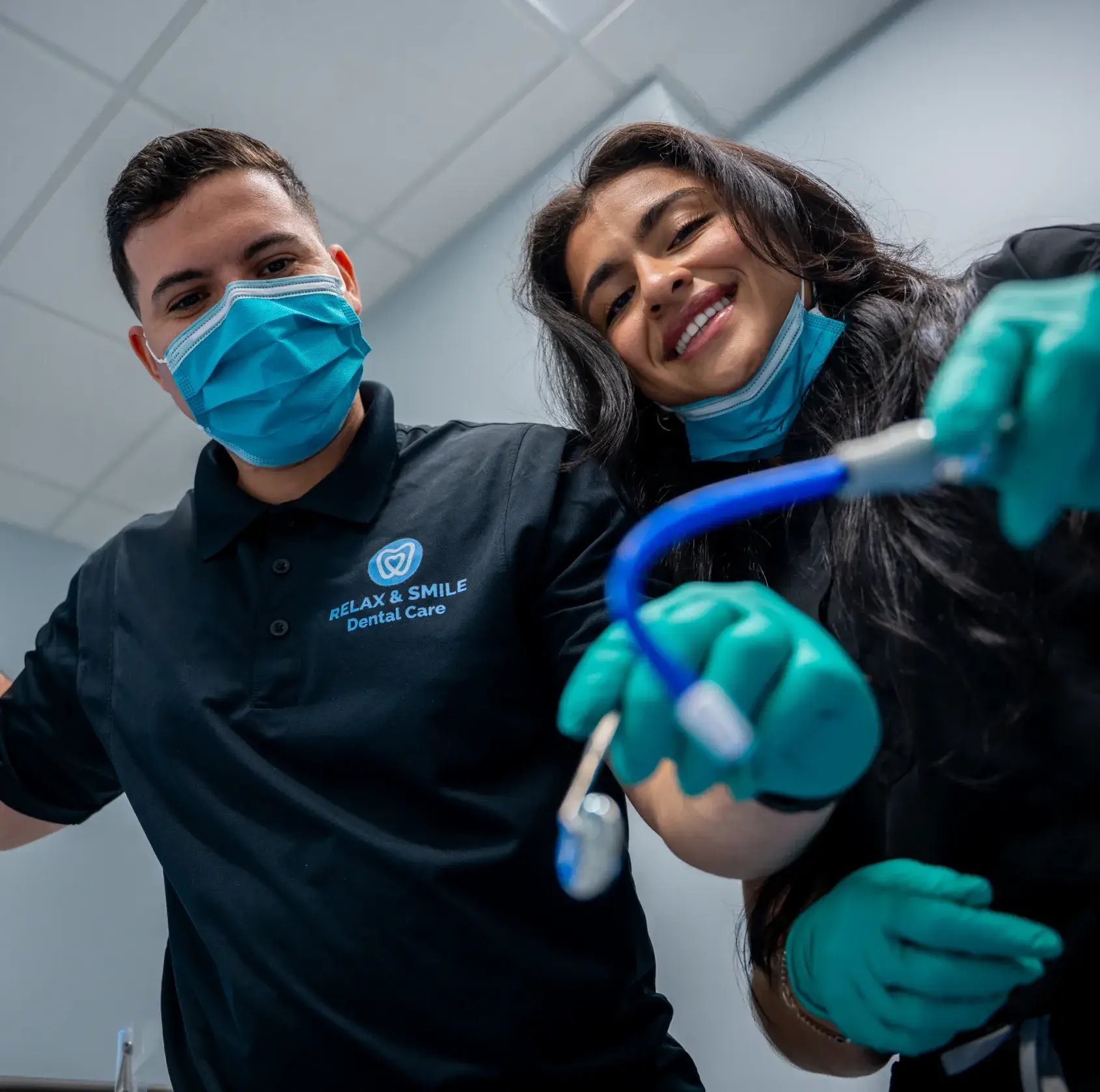 A dentist talks to a patient sitting in a dental chair, explaining something using a dental model.