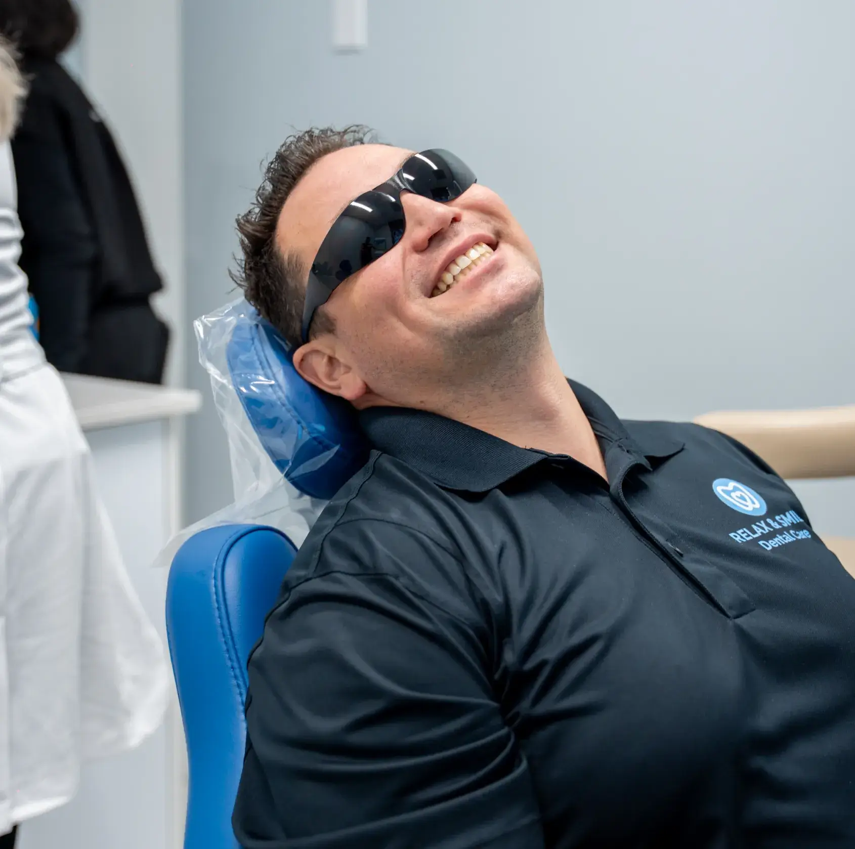 A dentist talks to a patient sitting in a dental chair in a clinic.