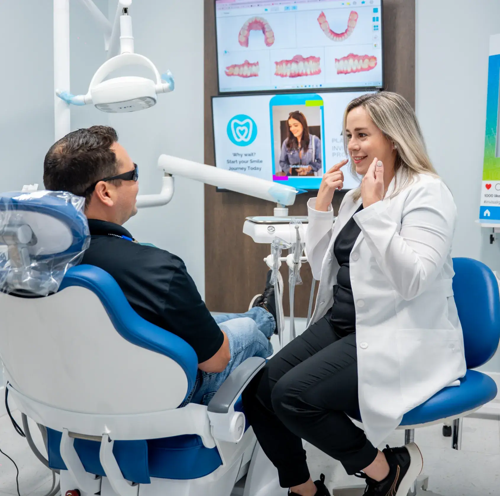 A dentist talks to a patient sitting in a dental chair at a clinic.