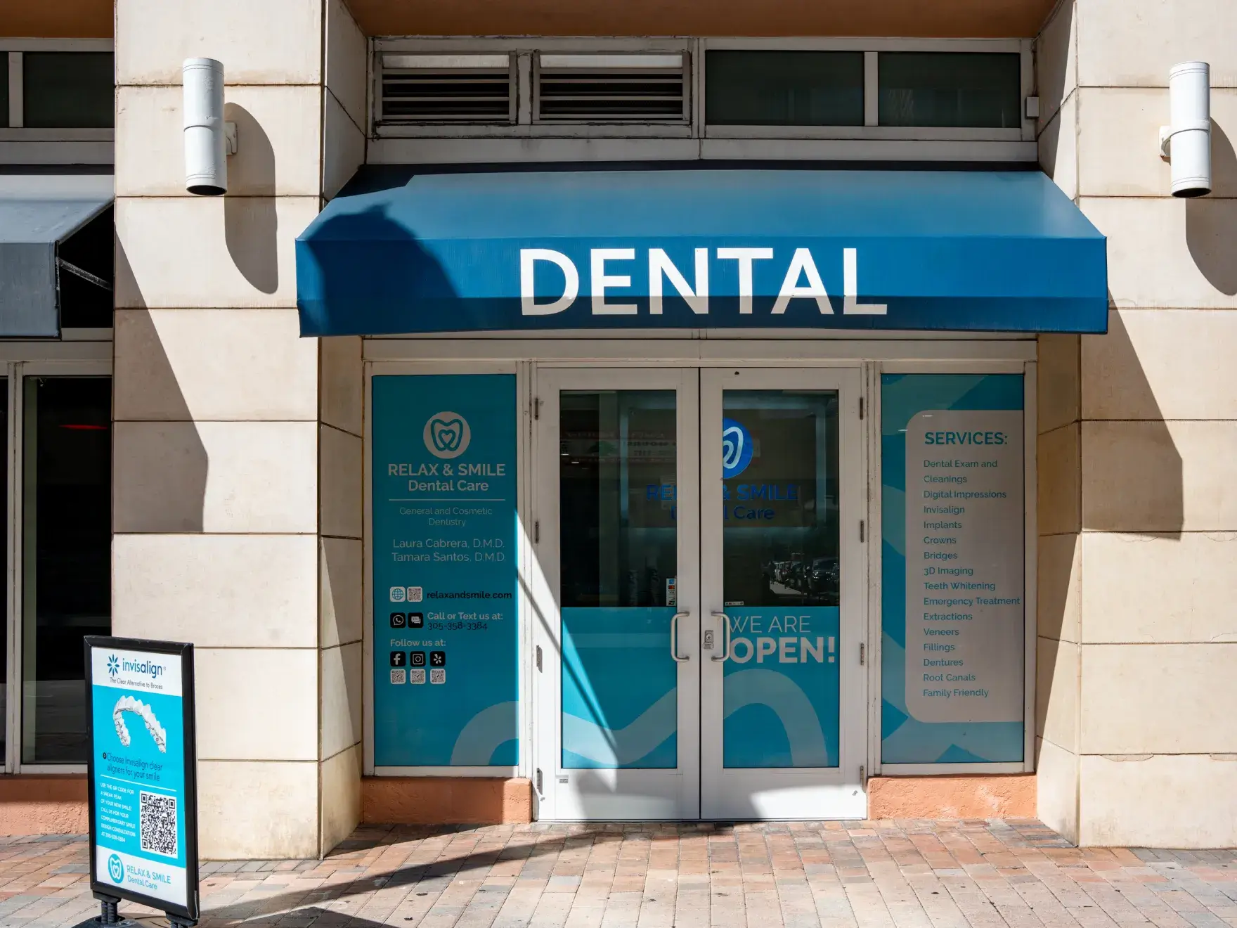 Four women in black tops smiling while leaning on a white counter in an office.