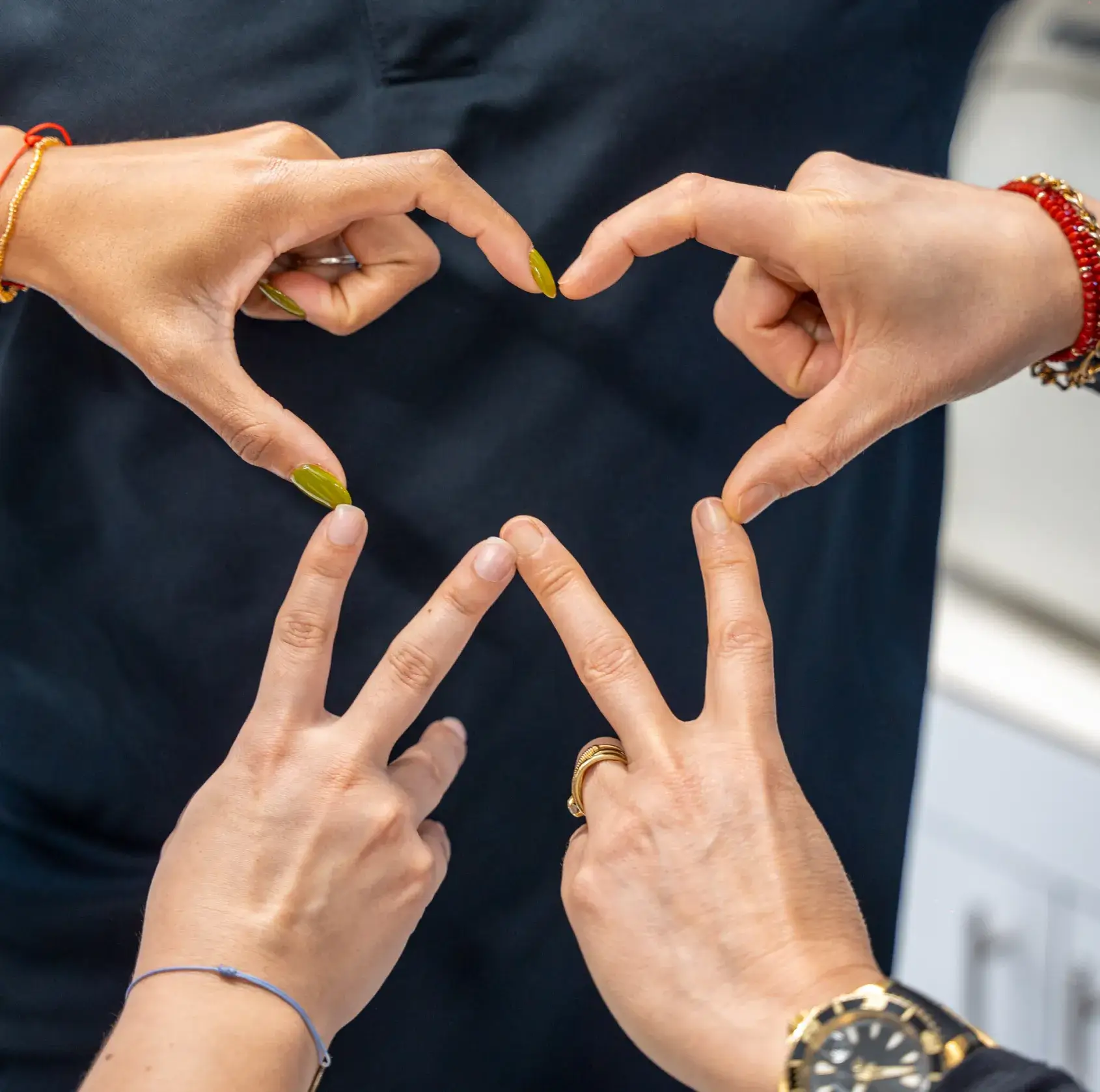 A group of people making a heart shape with their hands.