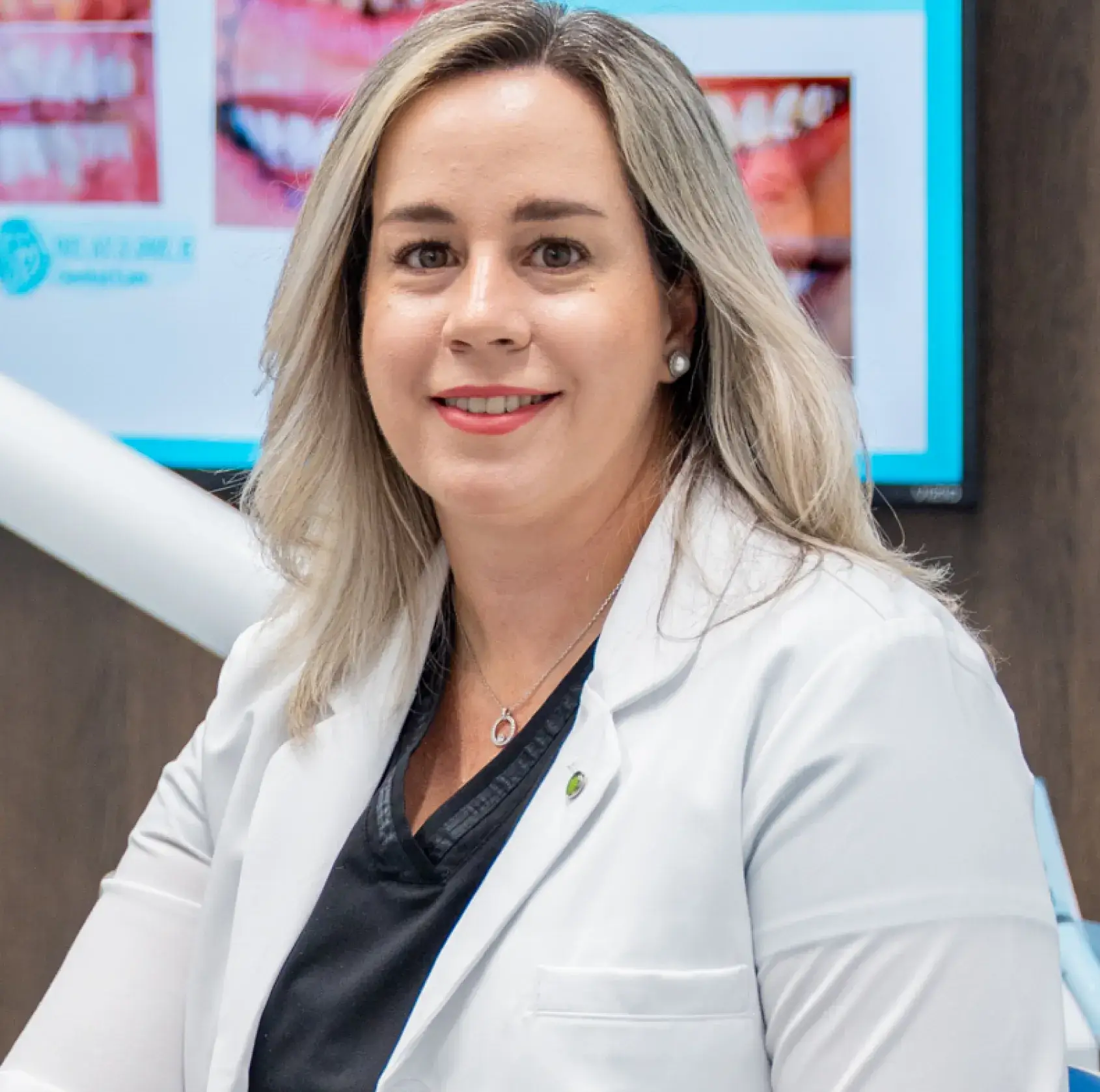 A woman in a white lab coat smiles at the camera.