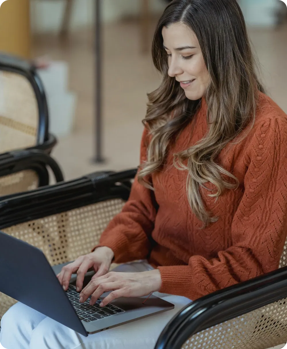 A girl studying on her computer while taking notes on a book