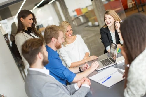 Design meeting: several people sit at the table and discuss the material on the screen.