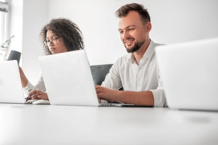 Two people at laptops in a minimalist office — focused teamwork.