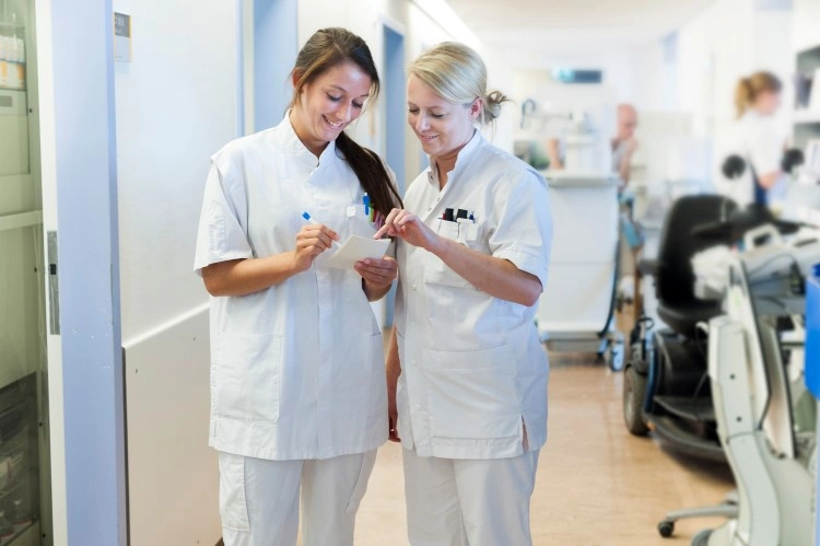 On-call duty in the ward — two nurses consult the recorded information in a bright corridor.