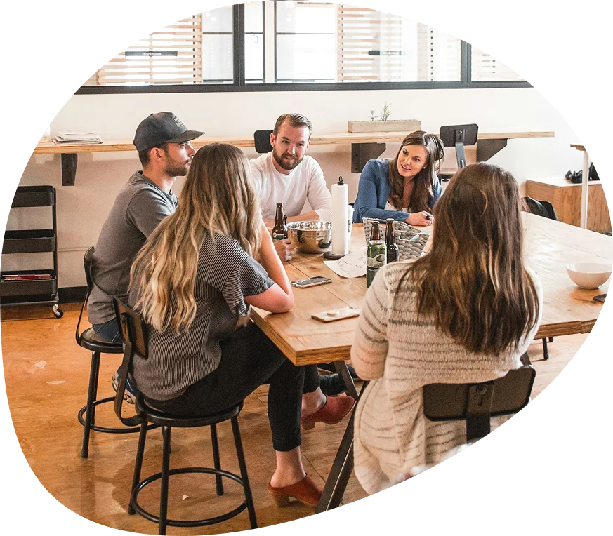 Team in a relaxed atmosphere — discussion at a large table in a bright room with high chairs.