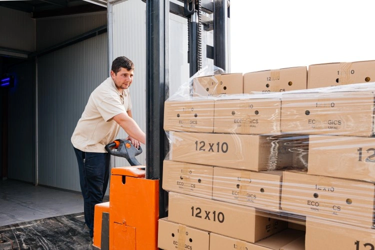 Shipping Zone: The man in the warehouse rearranges the packed cartons on a pallet.