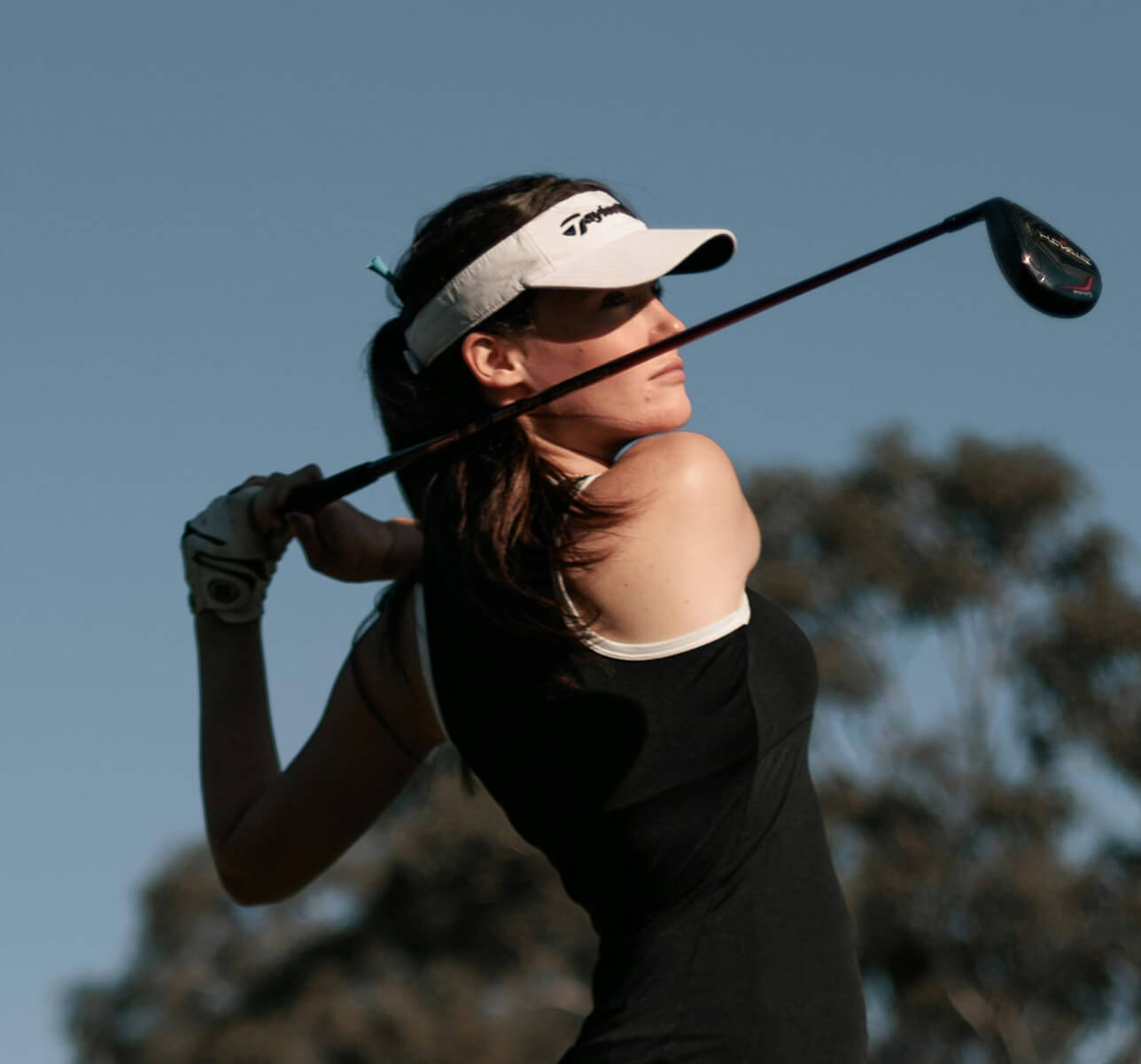 A female golfer holding her club behind her in a backswing.
