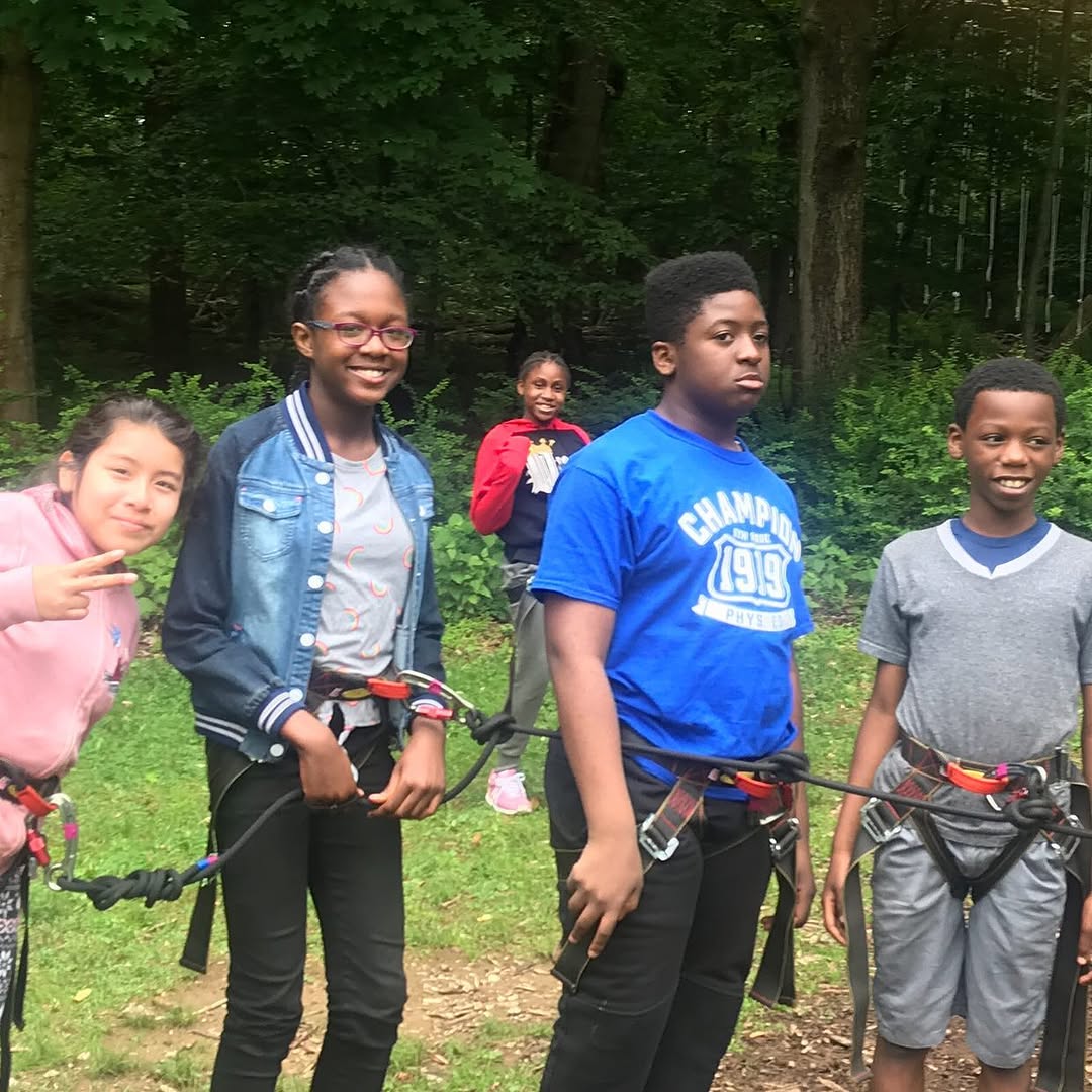 Students wearing climbing harnesses during an outdoor ropes course activity