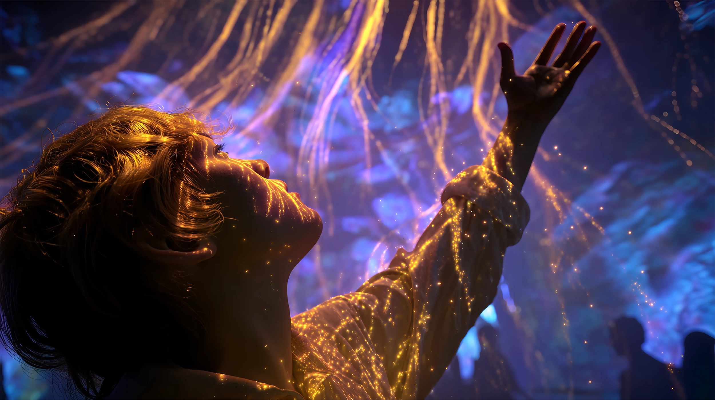 Person illuminated by swirling golden light patterns reaching upward against a dark, abstract blue background.