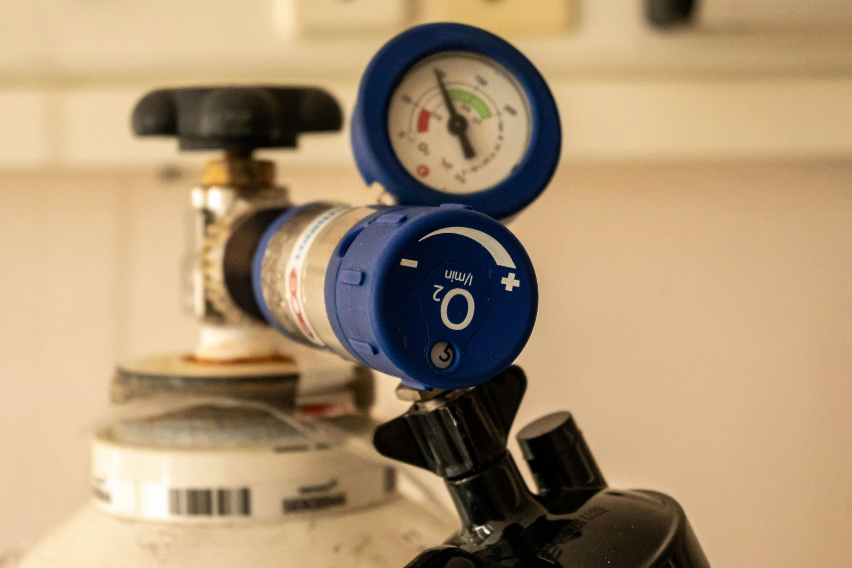 Close-up of an oxygen gas cylinder valve with pressure gauge and flow regulator.