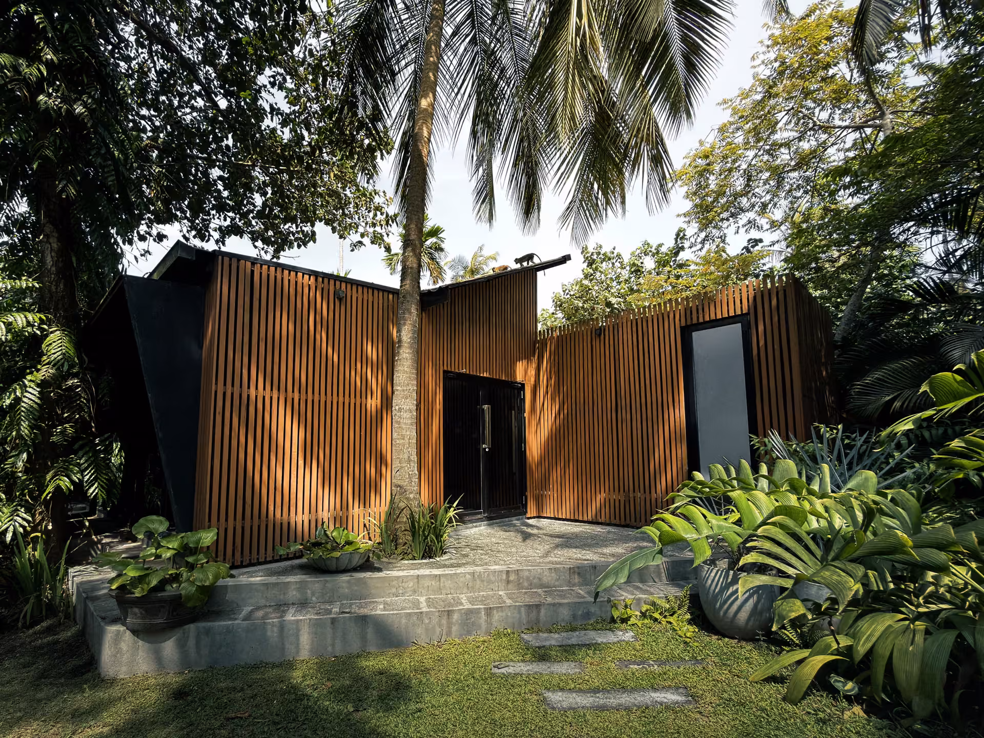 Licuala property entrance with timber-slat facade and coconut palm in the jungle garden, Ahangama, Sri Lanka