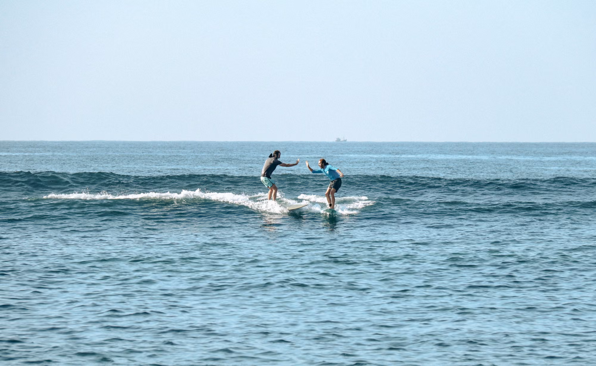 Two surfers sharing a wave at Kabalana beach near Licuala Lanka, Ahangama, Sri Lanka