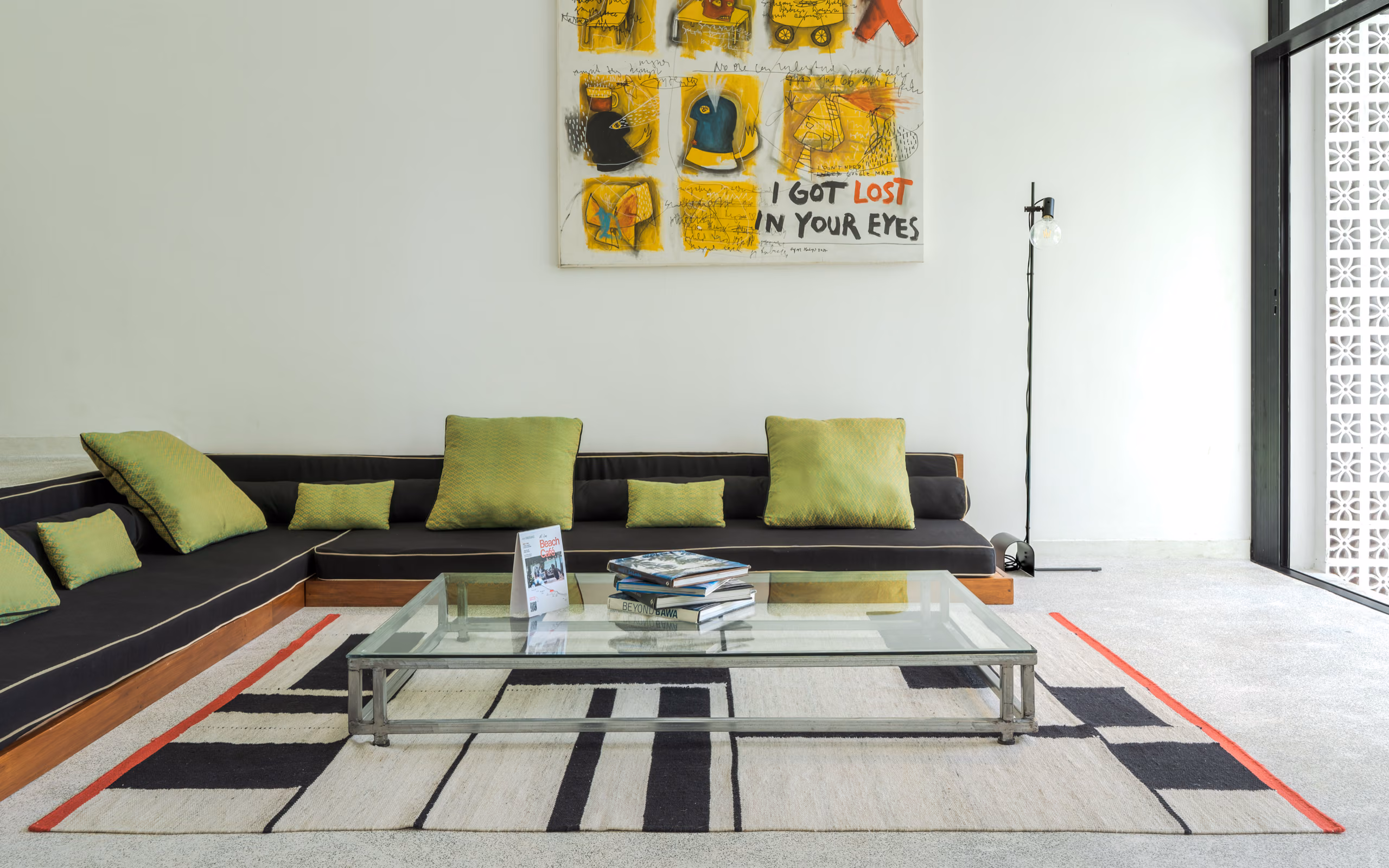 Living room with black lounge sofa and yellow artwork in the Garden House, Licuala Lanka, Ahangama, Sri Lanka