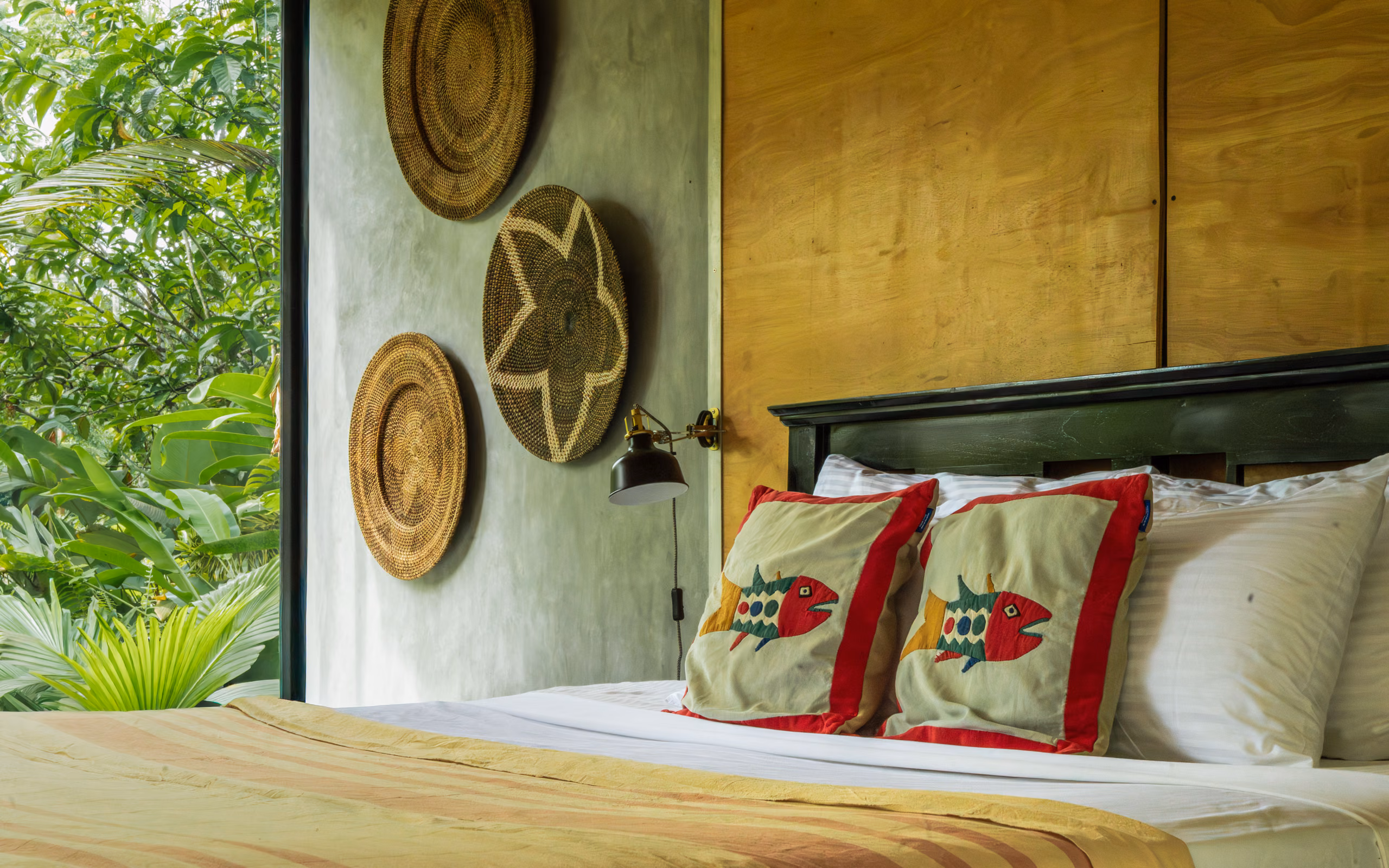 Bed with handmade fish cushions and woven wall decor in the Jungle Bungalow, Licuala Lanka, Ahangama, Sri Lanka