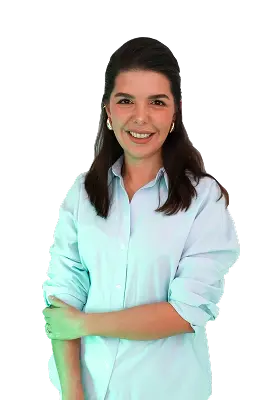 Smiling woman with long dark hair wearing a light blue button-up shirt with rolled-up sleeves.