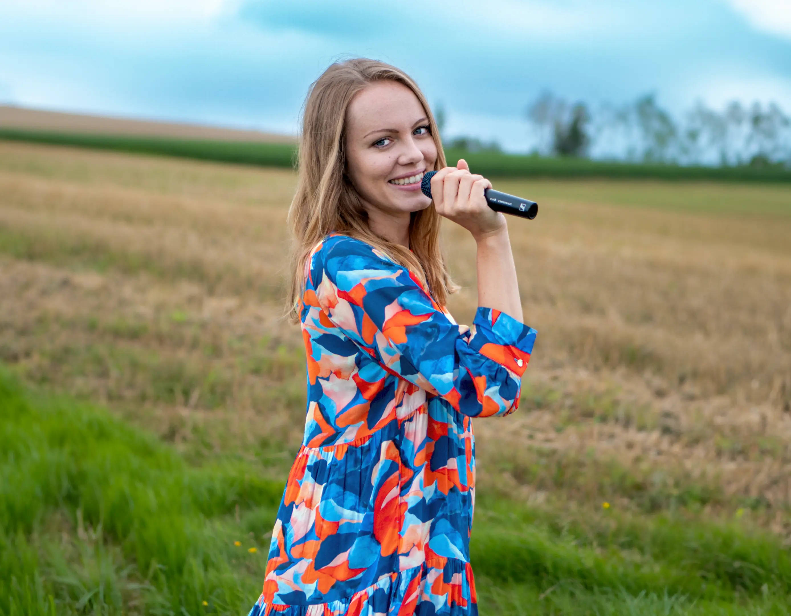 Martina singt mit Mikrofon auf einem Feld in Oberösterreich
