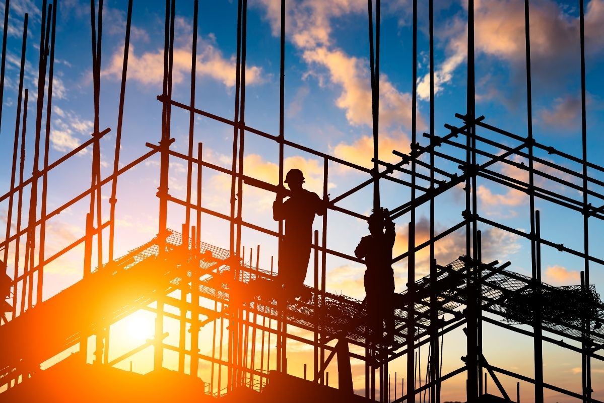 Trabajadores de construcción en andamios al atardecer, con logotipo de Diazar
