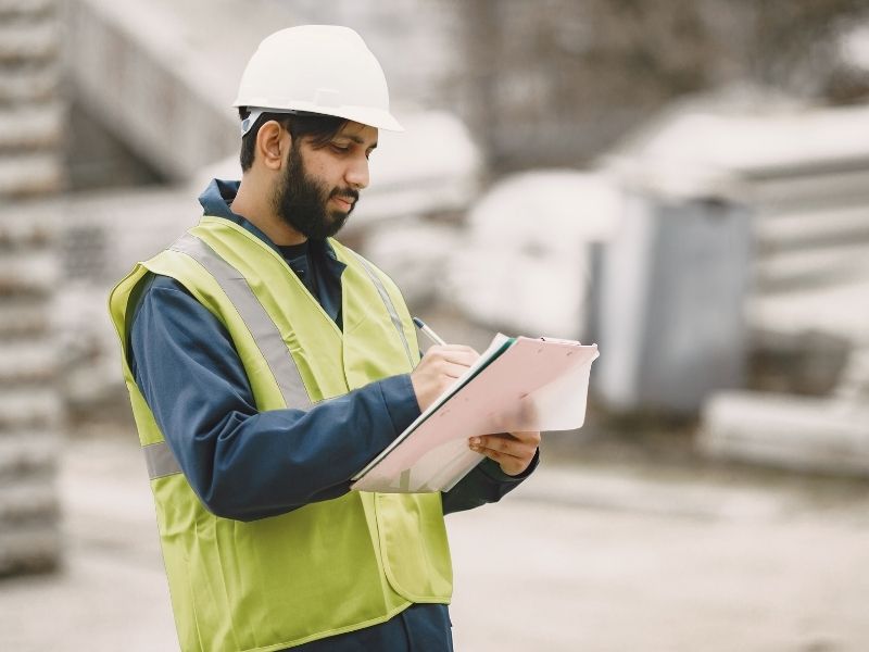 Supervisor de obra con casco y chaleco de seguridad registrando información en campo para dar seguimiento a actividades, avances y control del proyecto