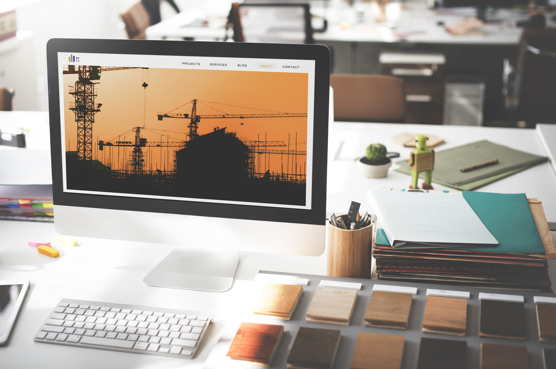 Monitor con imagen de una obra en construcción y muestras de materiales sobre una mesa de trabajo, representando la planeación, organización y gestión digital de proyectos de construcción con Diazar.
