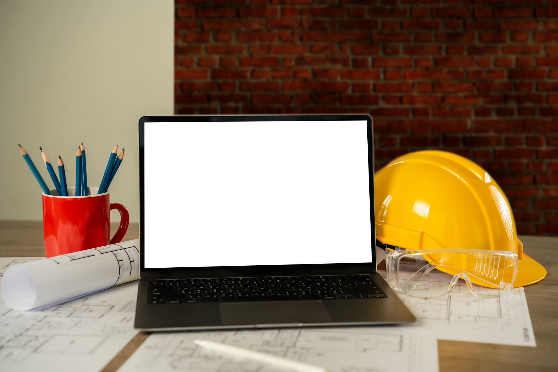 Laptop sobre planos de construcción junto a casco, lentes de seguridad y herramientas de trabajo, representando la digitalización y gestión integral de proyectos de obra con Diazar.