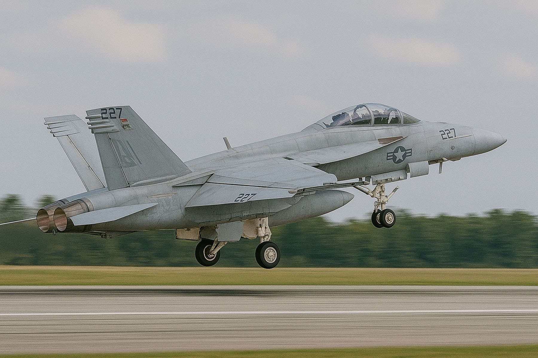 Gray military fighter jet with the number 227 taking off from a runway with trees in the background.