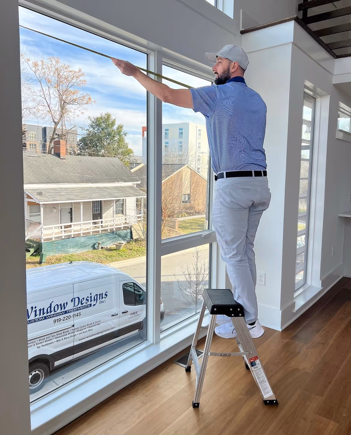 Matt Brooks on stepladder applying window treatment