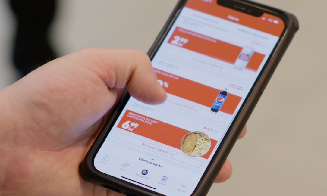 Hand using smartphone app with list of grocery offers