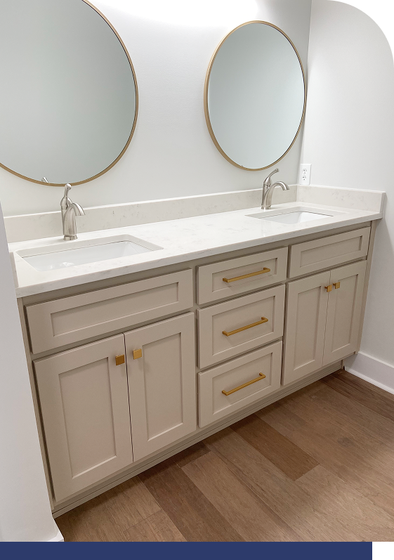 Double vanity bathroom with white shaker cabinetry and round mirrors