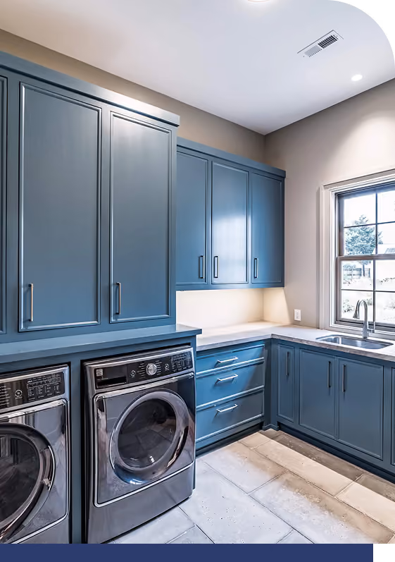 Blue laundry room cabinets with white countertops and washer/dryer