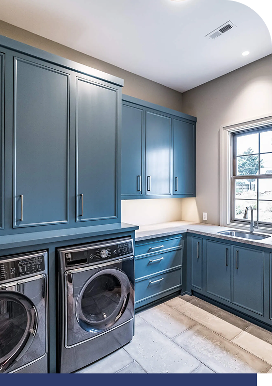 Blue laundry room cabinets with white countertops and washer/dryer