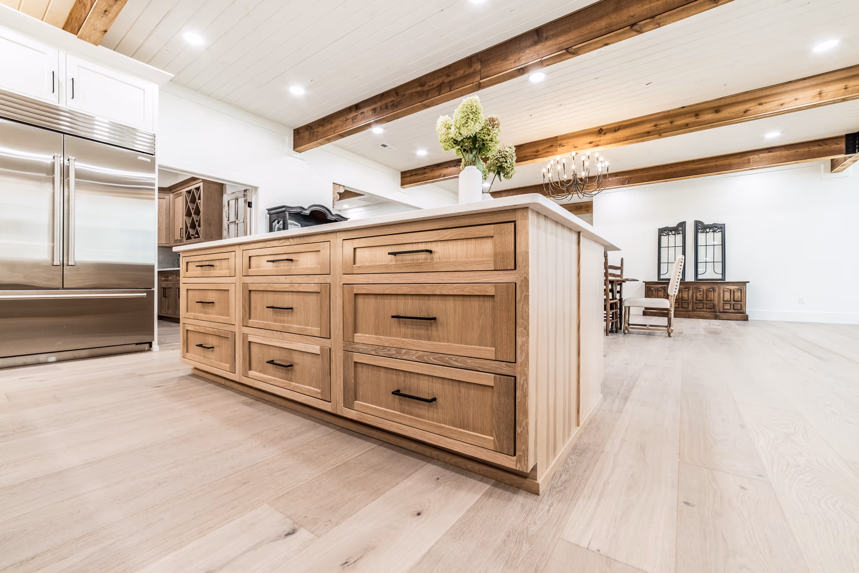 Kitchen island with natural wood cabinetry and overhead beams