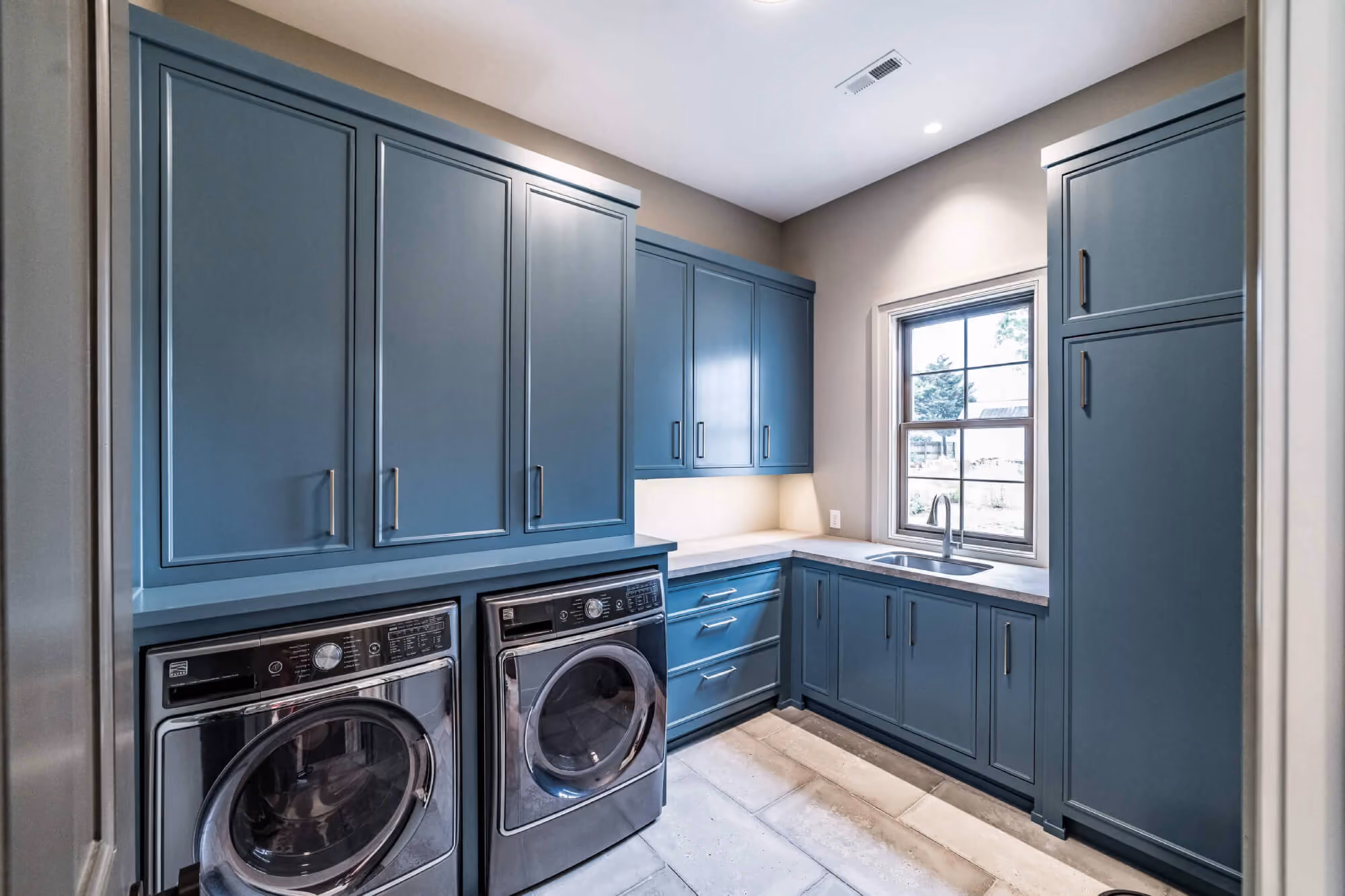 Blue custom laundry cabinets with built-in utility sink