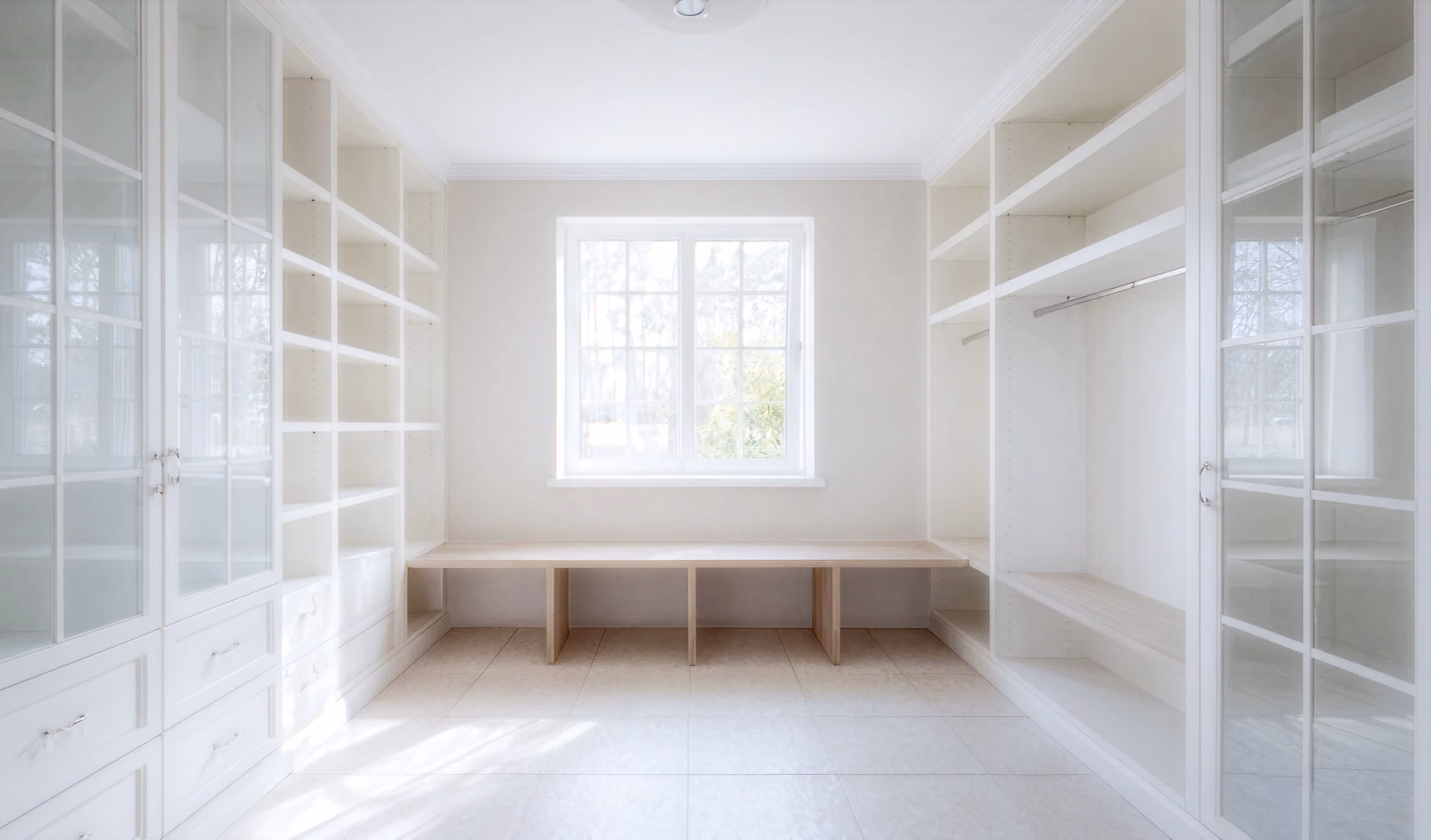 Minimalist white closet with built-in cabinetry and seating