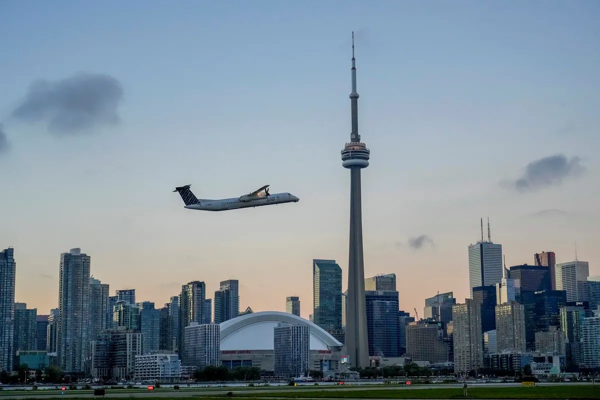 Toronto skyline at twilight with a plane flying in the sky above