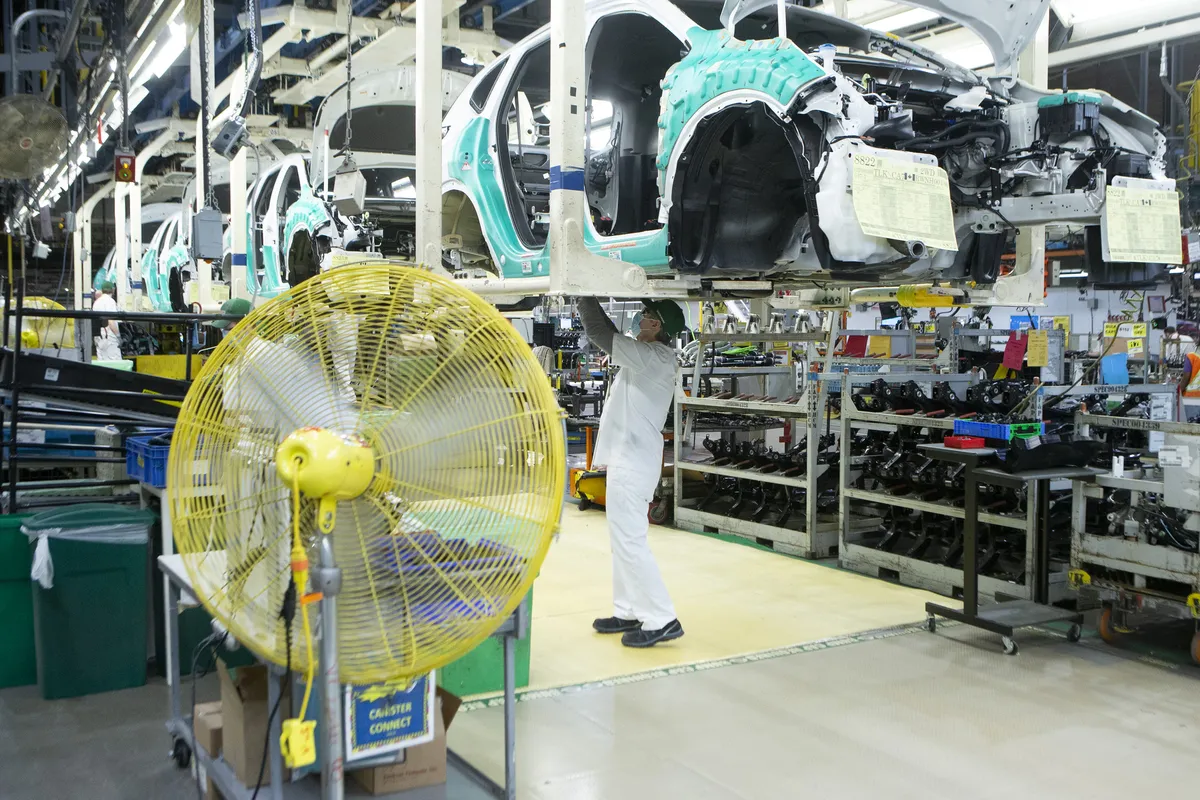An autoworker checks the underside of a car on a production line at a Honda plant.