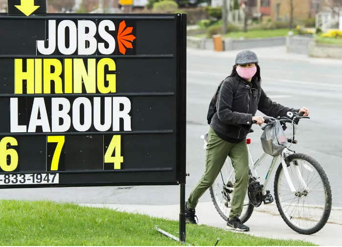 A woman checks out a jobs advertisement sign during the COVID-19 pandemic in Toronto