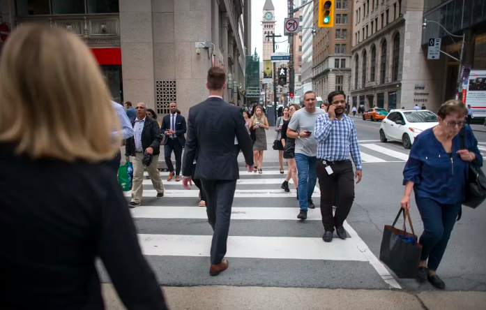 Office workers cross the street during a workday in downtown Toronto.