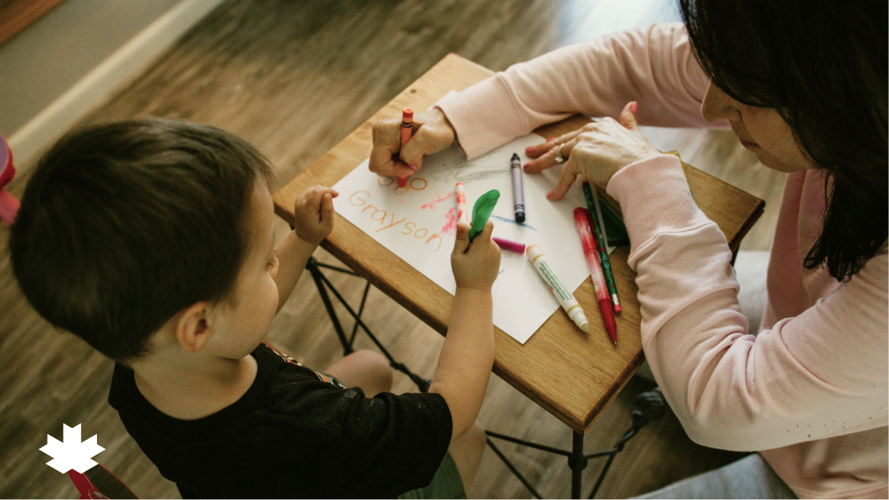 A women and child drawing with crayons