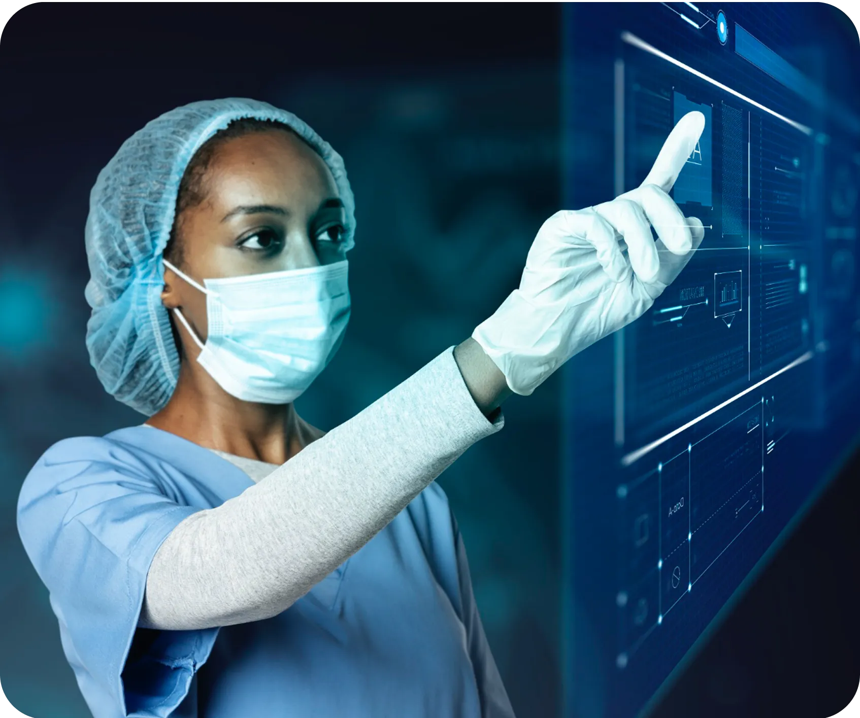 A woman in scrubs and a face mask points at a screen.