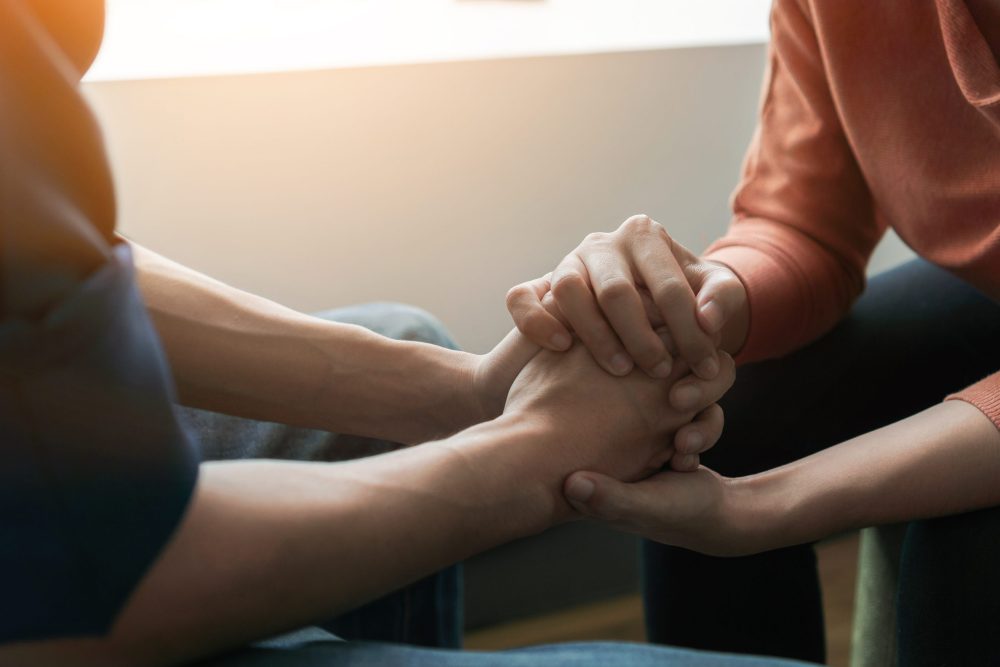 Two people holding hands and supporting each other during a family coaching session