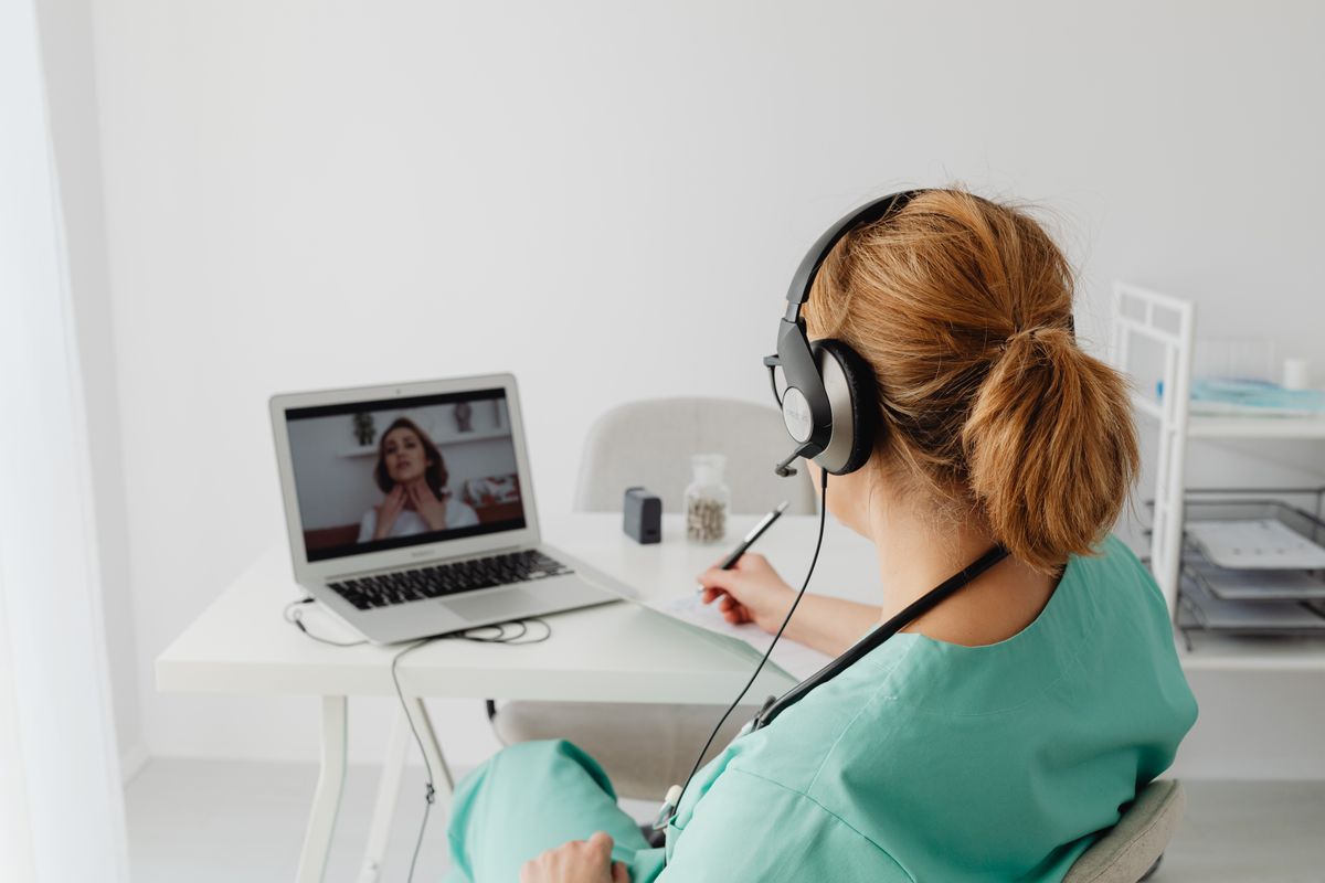 A clinician wearing a headset speaks with a person by video call; illustrative stock photograph