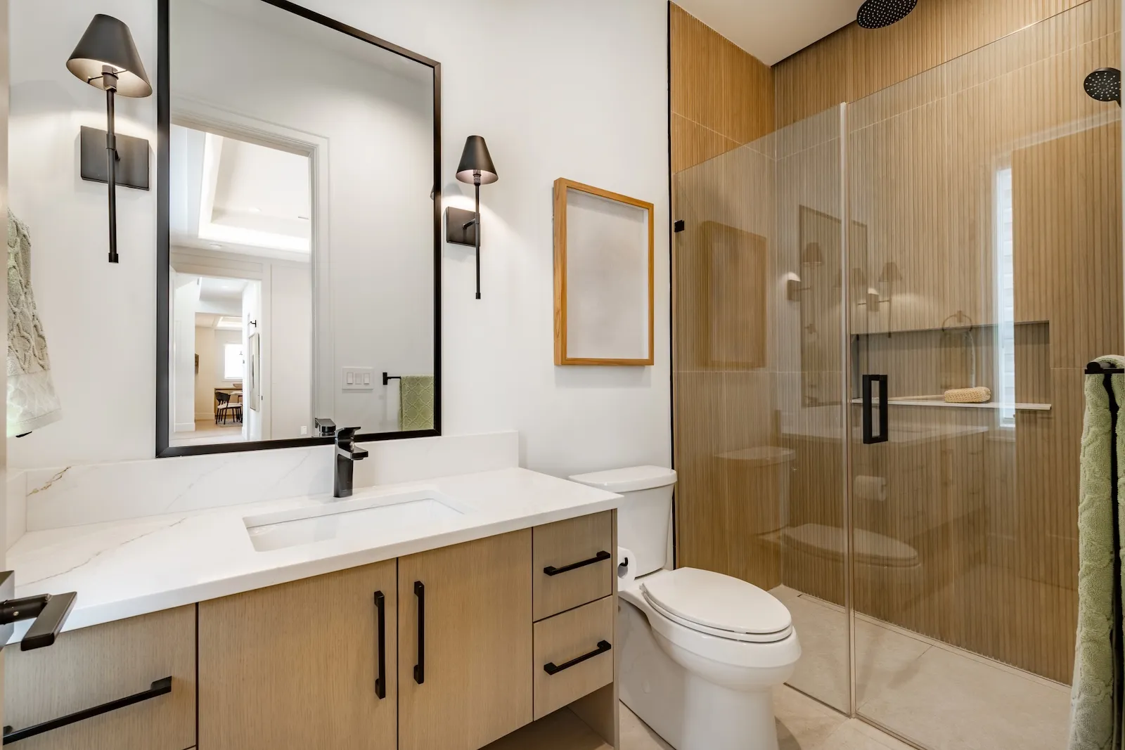 Contemporary bathroom remodel with natural wood vanity, frameless glass shower, marble countertops, and vertical tile accent wall in Toronto GTA